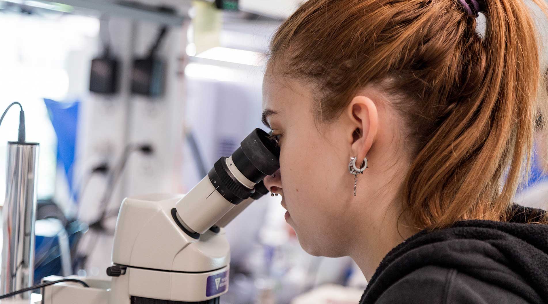 student looking through a microscope